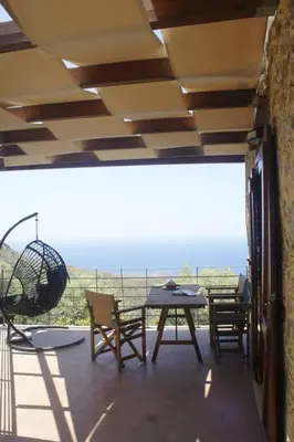 a patio with a table and chairs on a balcony at Rosales stone house in AmigdhalokeFálion