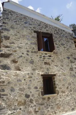 a stone building with three windows on it at Rosales stone house in AmigdhalokeFálion