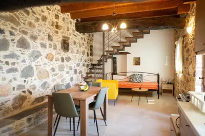 a room with a stone wall and a dining table and chairs at Alegria stone house in AmigdhalokeFálion