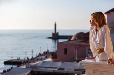a woman standing on a ledge looking out at the ocean at La Torre Residenza Imperiale in Chania Town