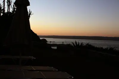 a sunset over the ocean with a beach umbrella at kera apartments in Kalyves