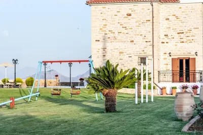a playground in a yard with a palm tree and swings at Ktima Edem in Ramní