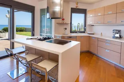 a kitchen with a large white island with stools at Villa Pasiphae in Stalos