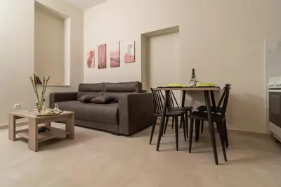 a living room with a couch and a table and chairs at Gemma Apartments in Palaiochóra