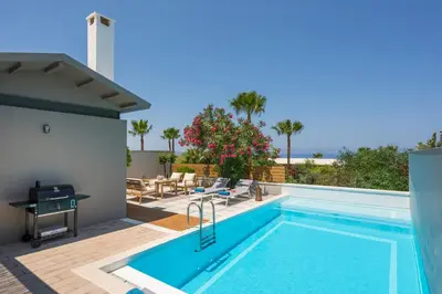 a swimming pool on a patio with a table and chairs at Natura Hill Villa III Sunset View in Kounoupidhianá