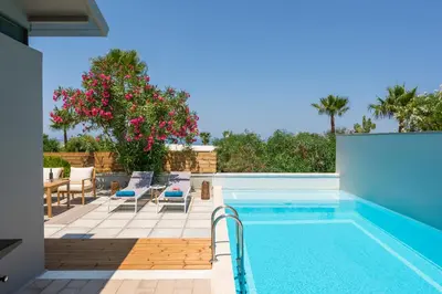 a swimming pool with lounge chairs and a villa at Natura Hill Villa III Sunset View in Kounoupidhianá