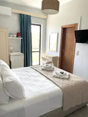 a bedroom with a large white bed with towels on it at wave rooms sea view in Maleme