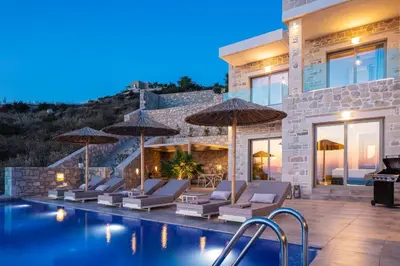 a villa with a swimming pool with chairs and umbrellas at Flower Village in Chania Town