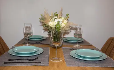 a table with plates and glasses and a vase of flowers at Inner City Retreat Apartment in Chania Town
