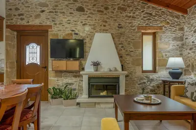 a living room with a stone wall with a fireplace at Anthea Cottage in Kaloudhianá