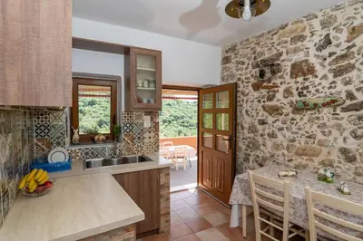 a kitchen with a table and a stone wall at Kantoni traditional house in Maláthiros