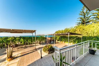 a patio with umbrellas and the ocean in the background at House On The Beach In Kera - BY APOKORONAS VILLAS in Kalyves