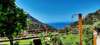 a fence on a hill with the ocean in the background at Place of the Gοds in Palaiochóra