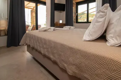 a large bed in a room with windows at Place of the Gοds in Palaiochóra