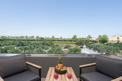 a balcony with two chairs and a table with a bowl of fruit at Aspect Luxury Apartments with Pool in Galangádhos