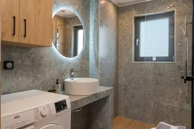 a bathroom with a sink and a washing machine at Aspect Luxury Apartments with Pool in Galangádhos