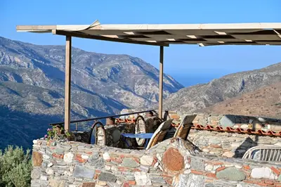 a table and chairs on top of a building with mountains at Velanos Villas in Kefálion