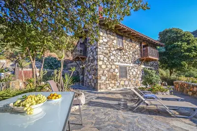 a table with a bowl of fruit in front of a house at Velanos Villas in Kefálion