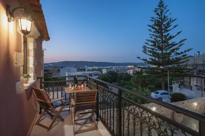 a balcony with a table and chairs and a christmas tree at Villa Eliomylos in Souda