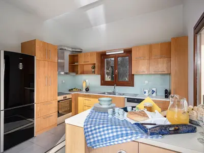 a kitchen with wooden cabinets and a table with bread at Villa Magia in Stérnai