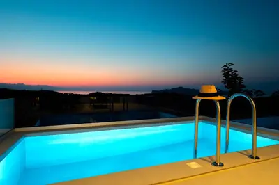 a hat sitting next to a swimming pool at sunset at Evora Suites in Chania Town