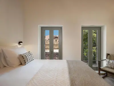 a white bedroom with a large bed and two windows at Theros Home in Chania Town