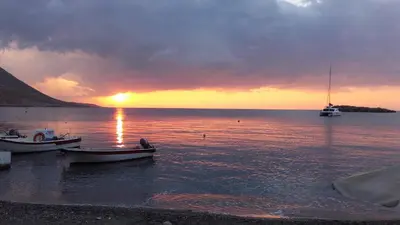 two boats on the water with a sunset in the background at Notos Rooms in Loutro