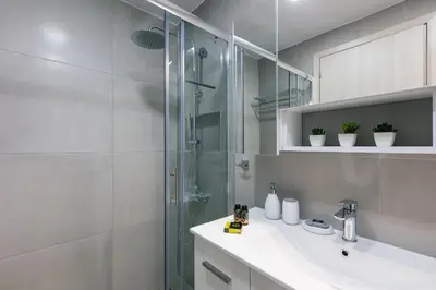 a bathroom with a sink and a glass shower at Estia Comfort House in Chania Town