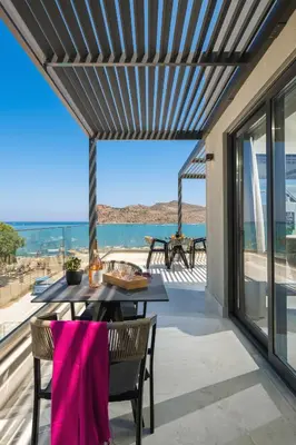 a patio with a table and chairs and a view of the ocean at Elia Agia Marina Resort in Agia Marina Nea Kydonias