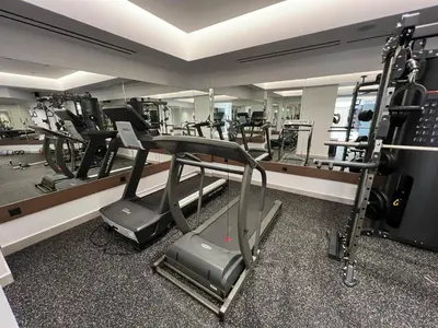 a gym with treadmills and ellipticals in front of a mirror at Elia Agia Marina Resort in Agia Marina Nea Kydonias