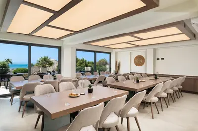 a conference room with tables and chairs and windows at Elia Agia Marina Resort in Agia Marina Nea Kydonias