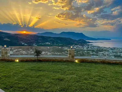 a view of a city with the sunset in the background at Korfali Apartments in Kissamos
