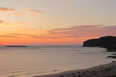 a sunset over a beach with a group of people at Seaside Escape in Nopíyia