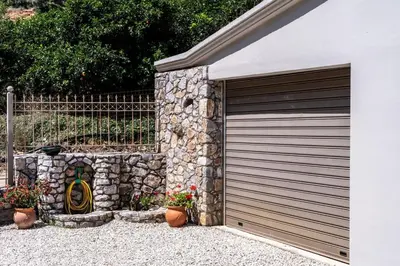 a garage with a garage door next to a stone wall at Villa Emily in countryside in Chania Town