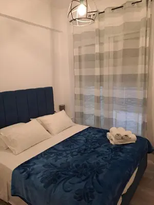 a bed with a blue blanket and two pairs of shoes on it at Parthenon apartment in Souda
