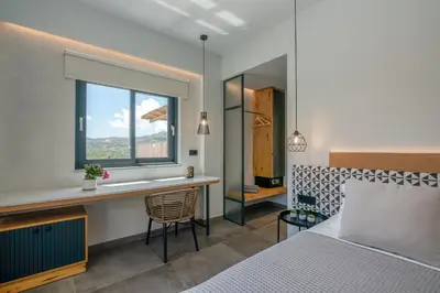 a bedroom with a bed and a desk and a window at Nusa Retreat - Seaview luxury residences - ideal for groups in Kissamos