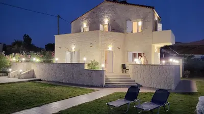 a man standing in front of a house at night at Villa Alex in Tavronitis