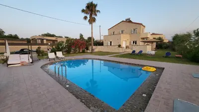 a swimming pool in front of a house at Villa Alex in Tavronitis