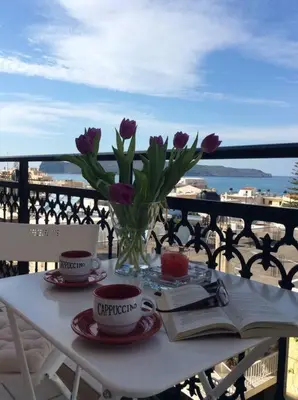 a table with two cups and a vase with purple flowers at Sea View Apartment #2 in Stalos