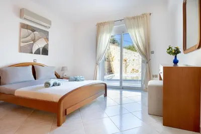 a bedroom with a bed and a sliding glass door at Iconic Villa with private pool and sea view in Próvarma