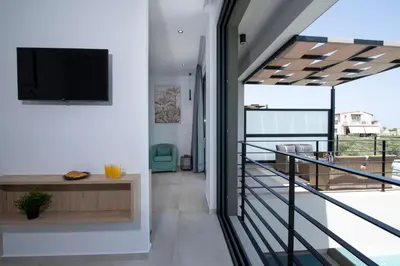 a room with a balcony with a tv on the wall at Cretan Queen Residences in Aghii Apostoli