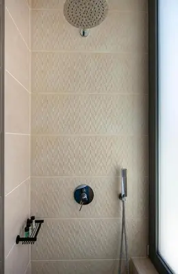 a shower with a white tiled wall at Cretan Queen Residences in Aghii Apostoli