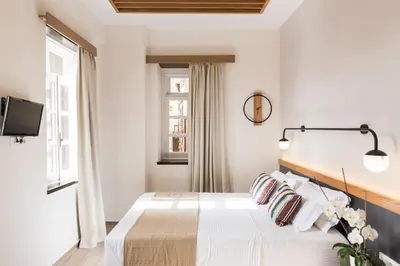 a white bedroom with a bed and a tv at Harismari Cozy Hotel in Chania Town