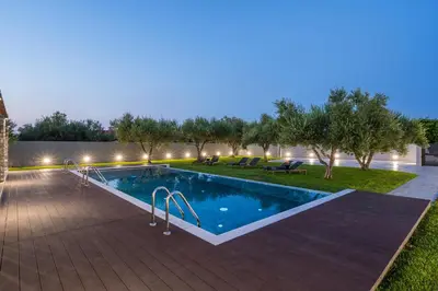 a swimming pool with a lit up backyard at night at Eightyfour Living with private pool in Chania Town