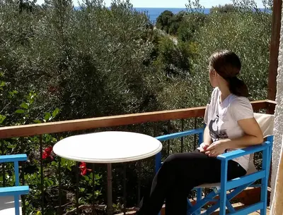 a woman sitting in a chair at a table at Olive tree Cottages in Palaiochóra