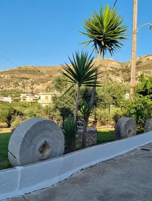 a row of large concrete objects in a park with palm trees at Casa Artemis in Plátanos