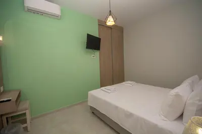 a bedroom with a white bed and a television at Korfali Apartments in Kissamos