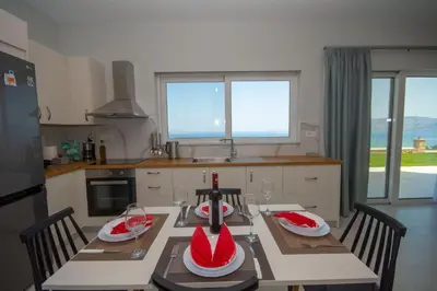 a kitchen with a table with two chairs and a kitchen withwindows at Korfali Apartments in Kissamos