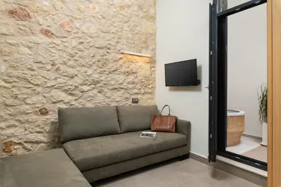 a living room with a couch and a stone wall at The Alma City Suites in Chania Town