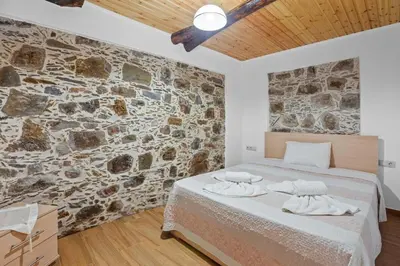 a bedroom with a bed and a stone wall at Maria's House with View in Kambos in Kámbos